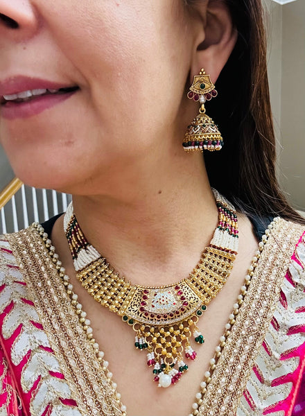 Gold plated necklace set with red green stones and meenakari